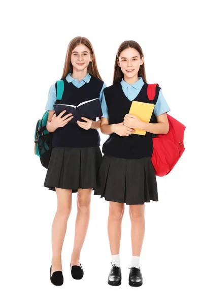 Retrato de comprimento total de meninas adolescentes em uniforme escolar com mochilas e livros sobre fundo branco — Fotografia de Stock