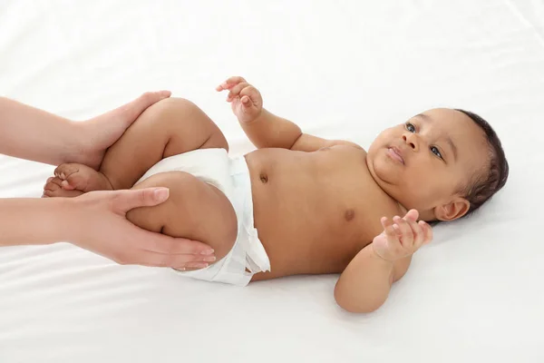 Anne ve tatlı çocuğu beyaz yatakta. Bebek masajı ve egzersizler. — Stok fotoğraf