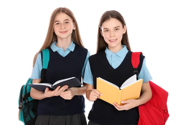 Портрет девочек-подростков в школьной форме с рюкзаками и книгами на белом фоне — стоковое фото