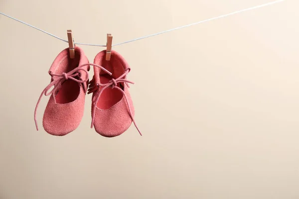 Śliczne małe buty wiszące na linii mycia przed kolorowym tłem, miejsce na tekst. Akcesoria dla niemowląt — Zdjęcie stockowe
