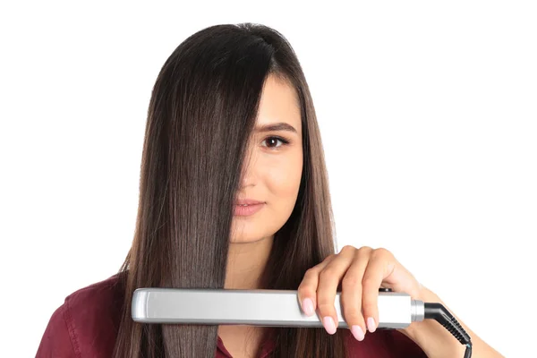 Young woman using hair iron on white background — Stockfoto