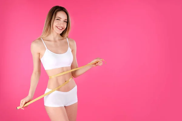 Mujer delgada midiendo su cintura sobre fondo de color, espacio para el texto. Cuerpo perfecto — Foto de Stock