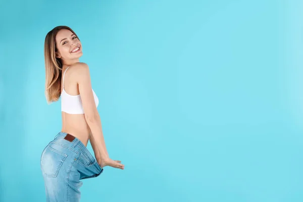 Mujer delgada en pantalones vaqueros de gran tamaño sobre fondo de color, espacio para el texto. Cuerpo perfecto — Foto de Stock