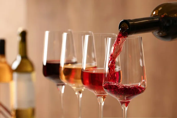 Pouring wine from bottle into glass on blurred background, closeup — Stock Photo, Image