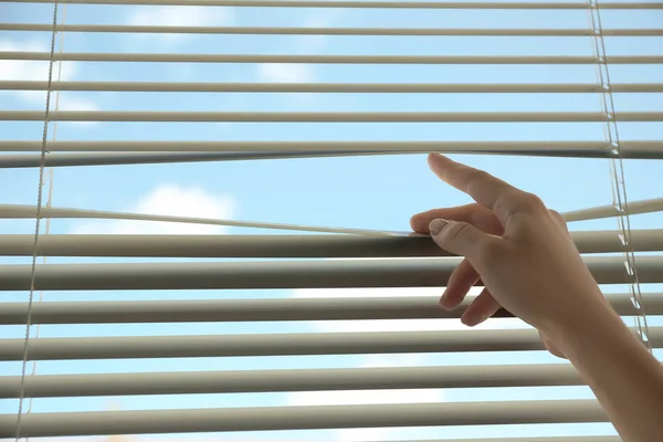 Woman opening horizontal window blinds at home, closeup. Space for text — Stock Photo, Image