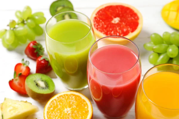 Glas med olika juicer och färsk frukt på träbord — Stockfoto