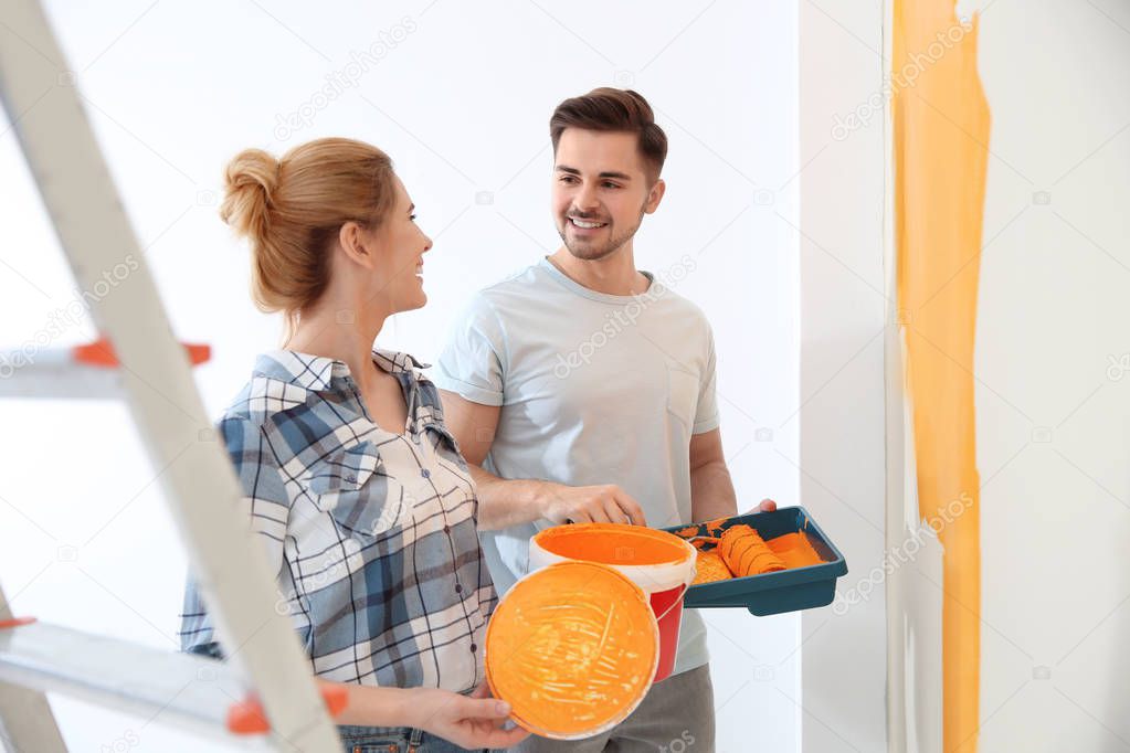 Happy couple painting wall indoors. Home repair