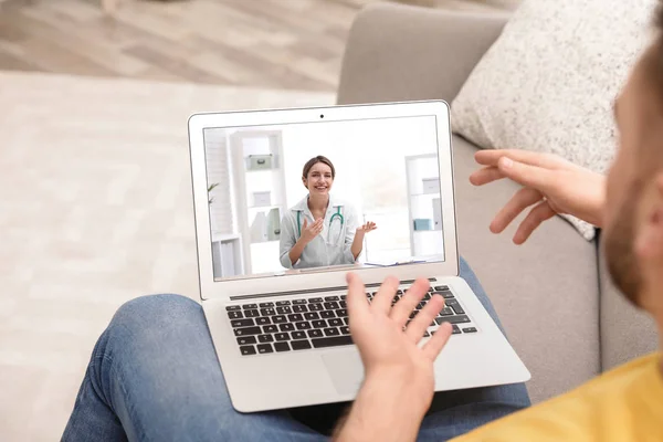 Uomo che utilizza il computer portatile per la consultazione online con il medico tramite video chat a casa, primo piano — Foto Stock