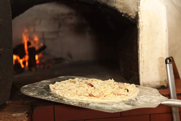 Sätta pizza i ugnen i restaurangkök — Stockfoto