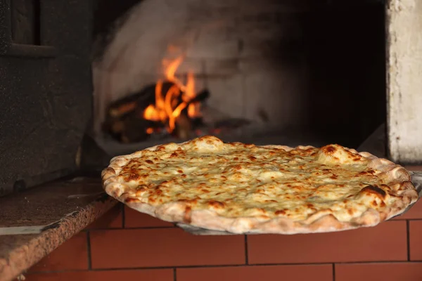 Ta välsmakande pizza ur ugnen i restaurangkök — Stockfoto