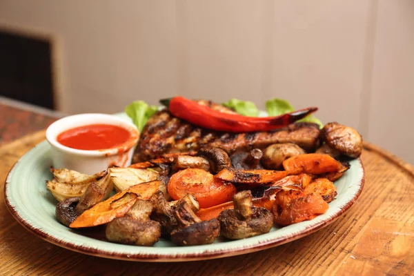 Plato con carne, guarnición y salsa sobre mesa de madera en restaurante. Receta de horno —  Fotos de Stock