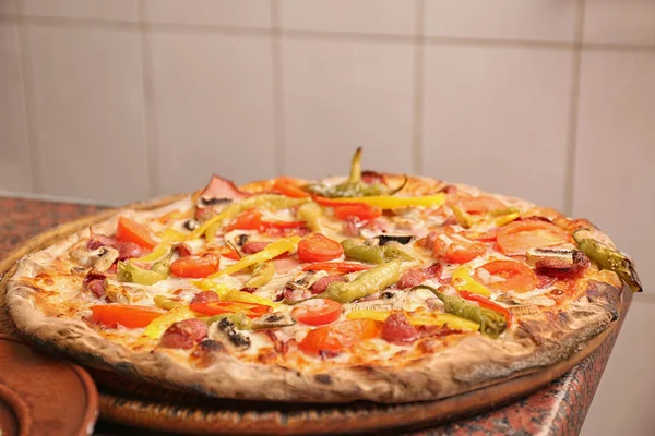 Träskiva med läcker pizza på bord i restaurang. Färsk från ugnen — Stockfoto