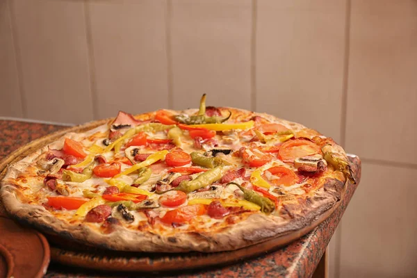 Träskiva med läcker pizza på bord i restaurang. Färsk från ugnen — Stockfoto