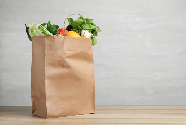 Bolsa de papel con verduras sobre la mesa sobre fondo gris. Espacio para texto — Foto de Stock