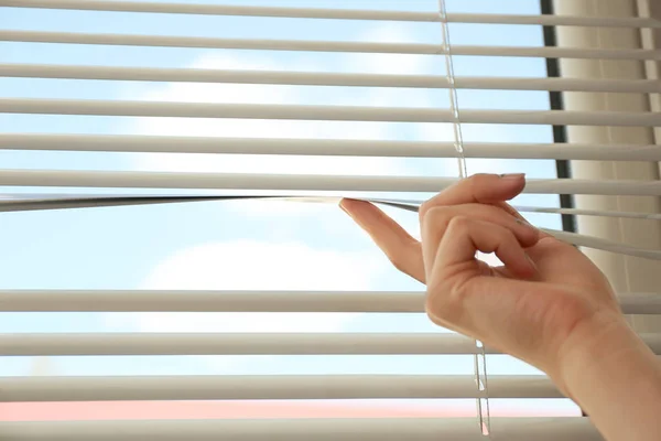 Woman opening horizontal window blinds at home, closeup. Space for text — Stock Photo, Image