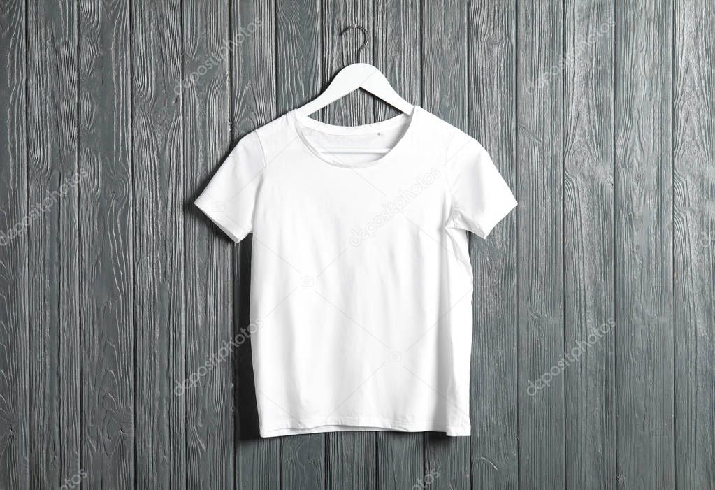 Hanger with white t-shirt on wooden background. Mockup for design