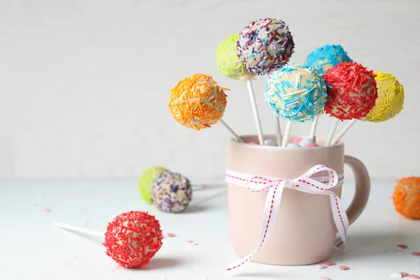 Beker met strik en lekkere kleurrijke cake Pops op tafel. Ruimte voor tekst — Stockfoto