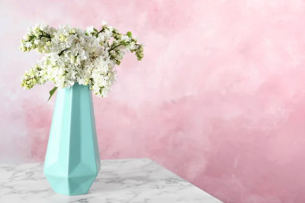 色の背景に対して大理石のテーブルの花瓶にライラックの花を開花。テキスト用のスペース — ストック写真