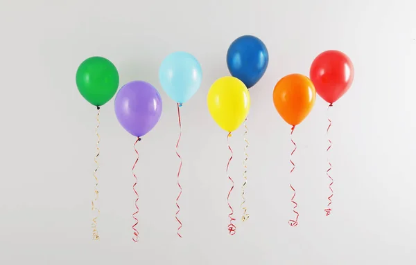 Különböző fényes ballonok a világos háttér. Ünneplés ideje — Stock Fotó