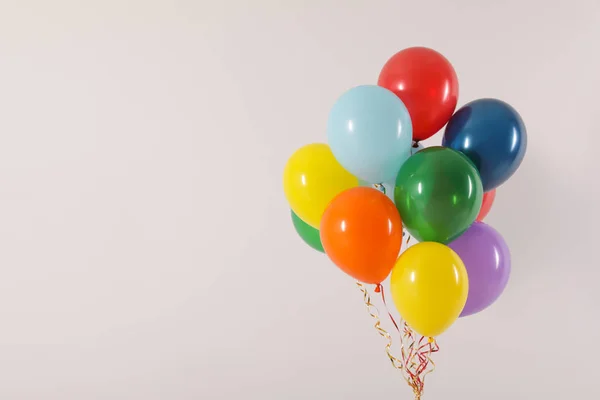 Stelletje heldere ballonnen op lichte achtergrond, ruimte voor tekst. Viering tijd — Stockfoto