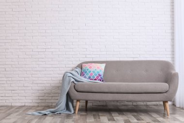 Rahat kanepe, yastık ve tuğla duvara yakın ekose ile Minimalist oturma odası iç. Metin için alan