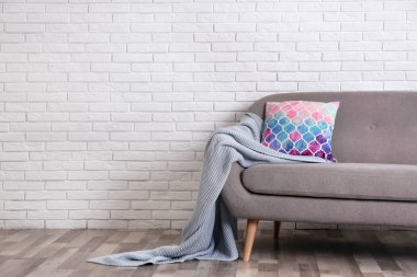 Rahat kanepe, yastık ve tuğla duvara yakın ekose ile Minimalist oturma odası iç. Metin için alan
