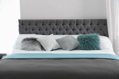 Farklı yastıklar ve hafif odada ekose ile rahat yatak. İç dekor için fikir