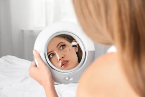 Jovem com problema de perda de pestanas olhando no espelho dentro de casa — Fotografia de Stock