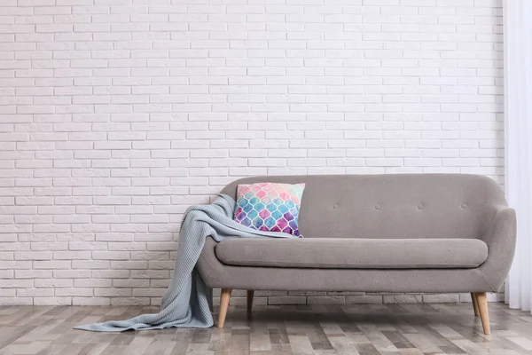 Rahat kanepe, yastık ve tuğla duvara yakın ekose ile Minimalist oturma odası iç. Metin için alan