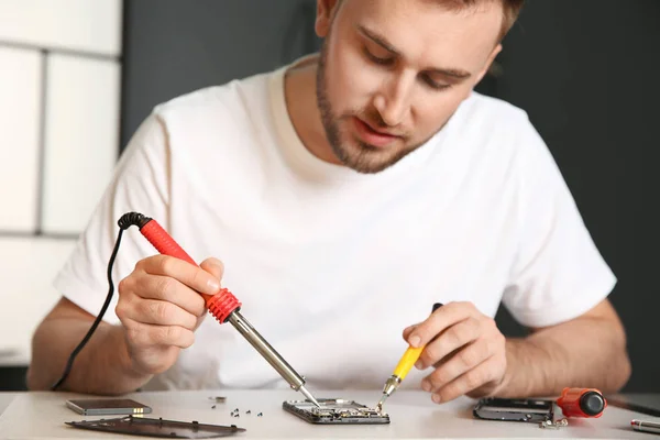 Technicien réparer téléphone portable à table dans l'atelier — Photo