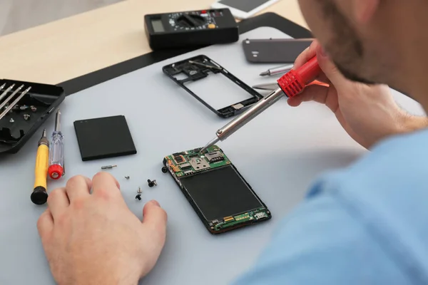 Técnico reparación de teléfonos inteligentes rotos en la mesa, primer plano —  Fotos de Stock