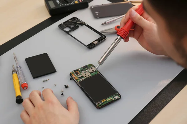 Técnico reparación de teléfonos inteligentes rotos en la mesa, primer plano —  Fotos de Stock