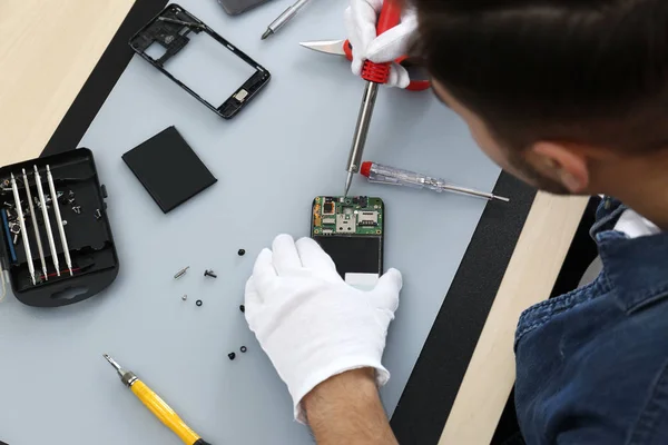 Técnico reparación de teléfonos inteligentes rotos en la mesa, primer plano —  Fotos de Stock