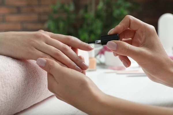 Manicura aplicando esmalte en las uñas del cliente en la mesa, primer plano. Tratamiento de spa —  Fotos de Stock