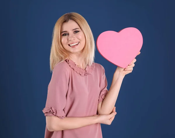 Bella donna con scatola a forma di cuore su sfondo di colore — Foto Stock