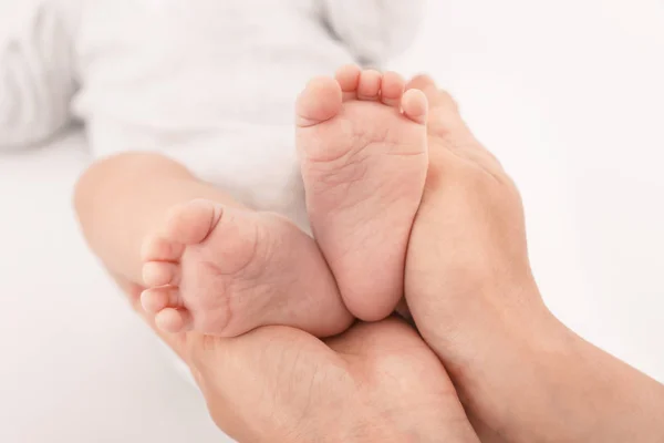 Matka držela dětské nohy na světle pozadí, v šatně — Stock fotografie