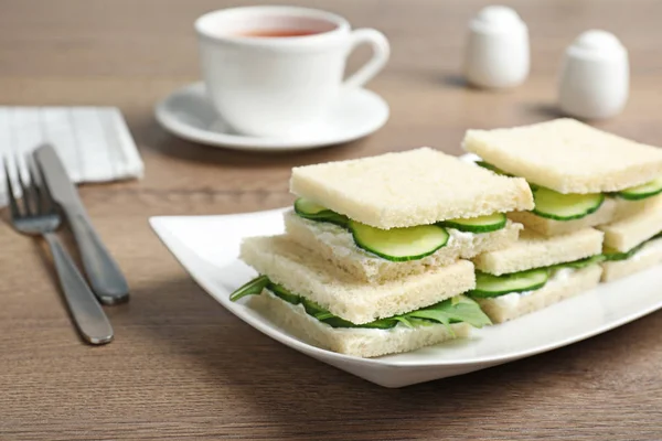 Plate with cucumber sandwiches served on wooden table. Space for text