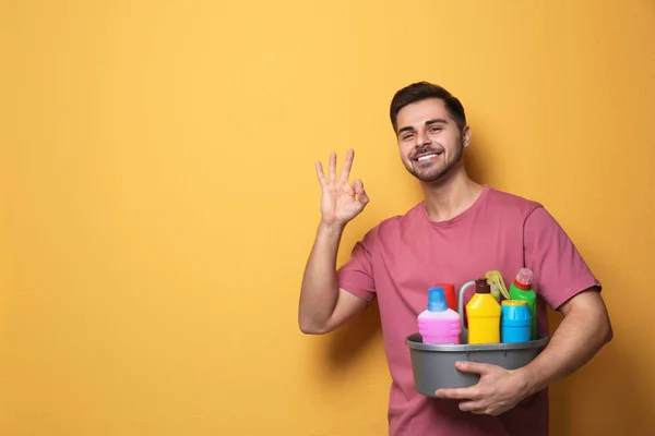 Człowiek z umywalką detergentów na kolorowym tle. Miejsce na tekst — Zdjęcie stockowe