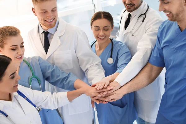 Jóvenes médicos poniendo las manos juntas en el interior. Concepto de unidad — Foto de Stock