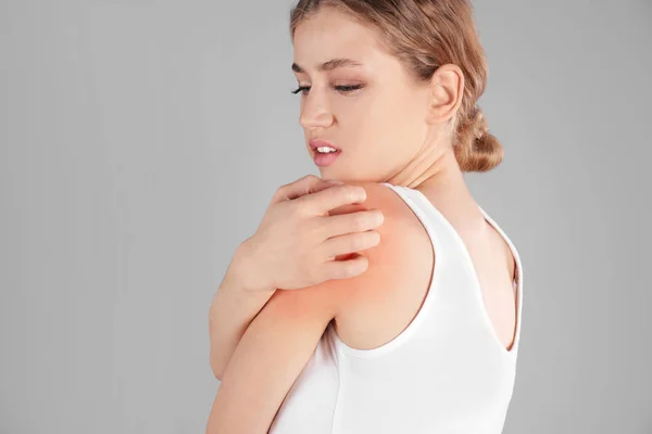 Mujer arañando hombro sobre fondo gris. Síntomas alérgicos — Foto de Stock