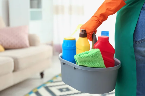 Vrouw met bekken van detergenten in de woonkamer, close-up. Schoonmaakservice — Stockfoto