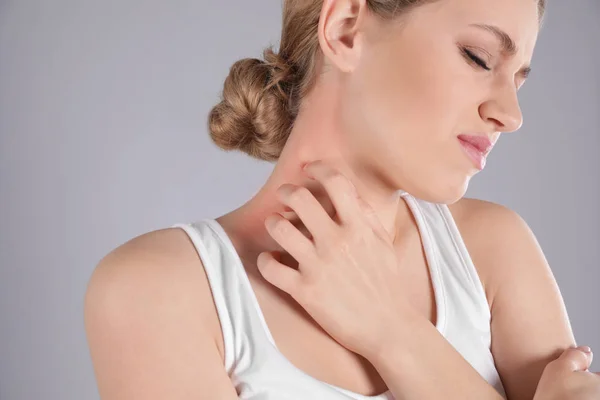 Mujer rascándose el cuello sobre fondo gris. Síntomas alérgicos — Foto de Stock
