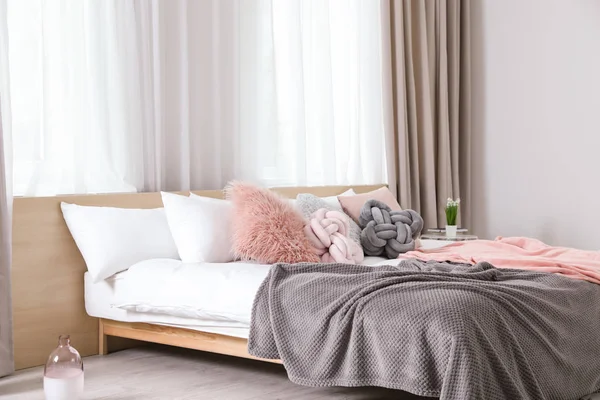 Cómoda cama con almohadas y cuadros en el interior de la habitación moderna — Foto de Stock