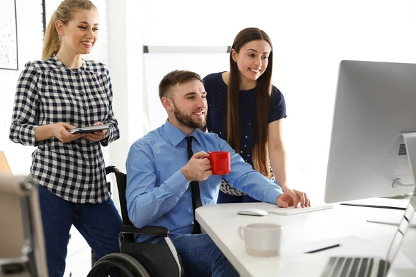 Człowiek na wózku inwalidzkim z kolegami w miejscu pracy — Zdjęcie stockowe