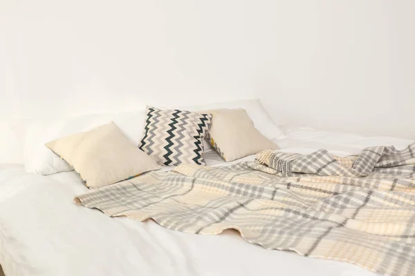 Łóżko z poduszkami i kratą w pobliżu światła ściany. Przytulny wystrój wnętrz — Zdjęcie stockowe