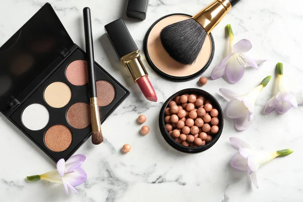 Veel verschillende make-up producten en lente bloemen op marmeren achtergrond, platte lay — Stockfoto