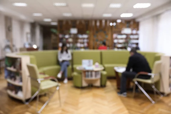 Wazig zicht op het interieur van de bibliotheek met ronde bankstel en boekenkasten — Stockfoto