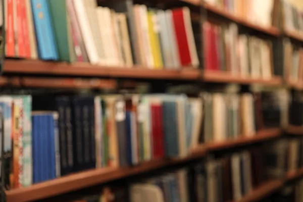 Vista borrosa de los estantes con libros en la biblioteca — Foto de Stock
