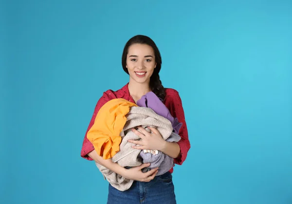 Gelukkige jonge vrouw Holding stapel vuile Wasserij op kleur achtergrond — Stockfoto