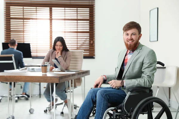 Junger Mann im Rollstuhl mit Kollegen im Büro — Stockfoto